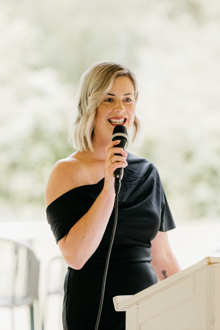 Nadhie spreekt met een microfoon tijdens een ceremonie