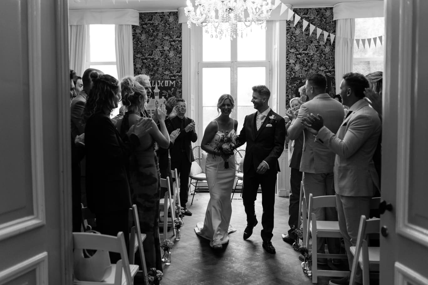 Bruidspaar loopt na de ceremonie tussen de gasten door