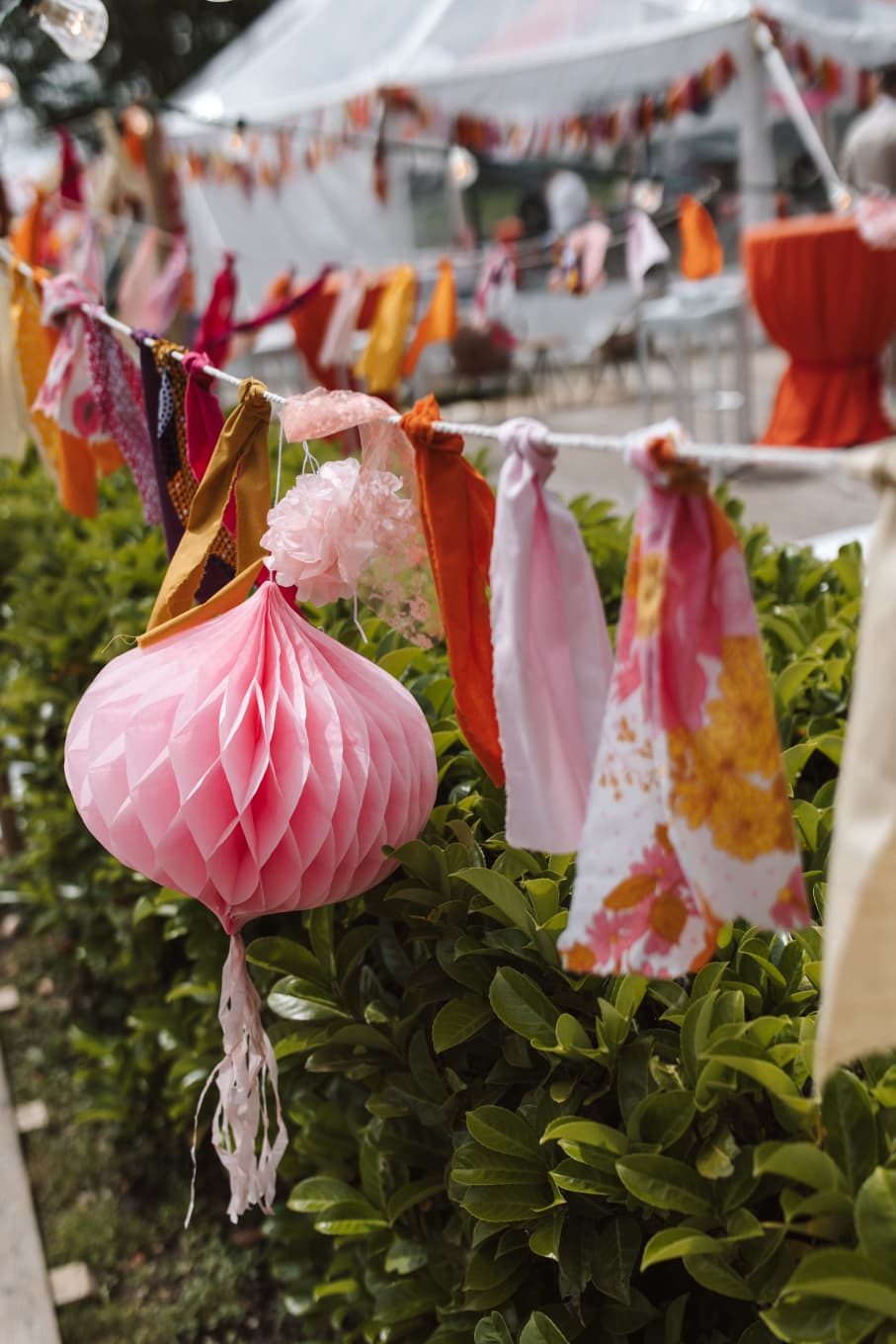 Roze lampion en stoffen linten in de haag
